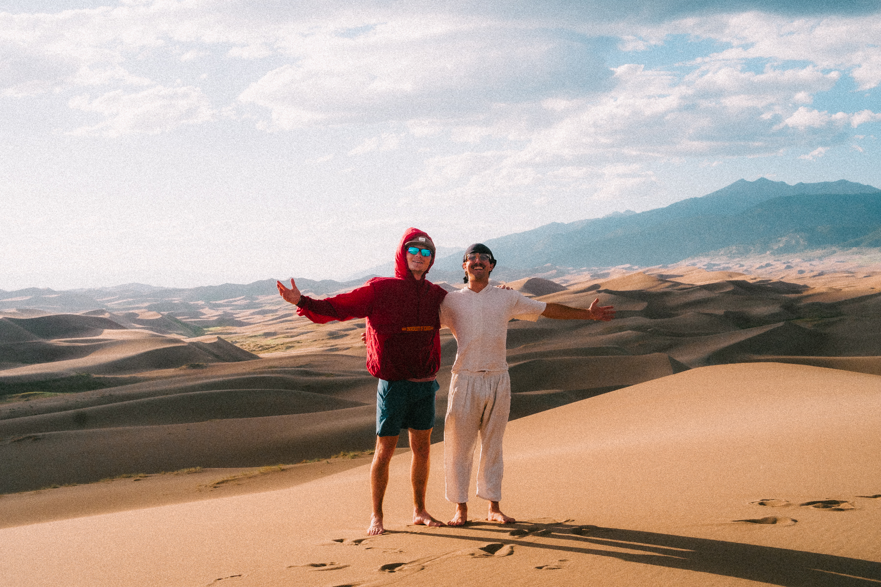 Two friends posing with arms wide at Great Sand Dunes